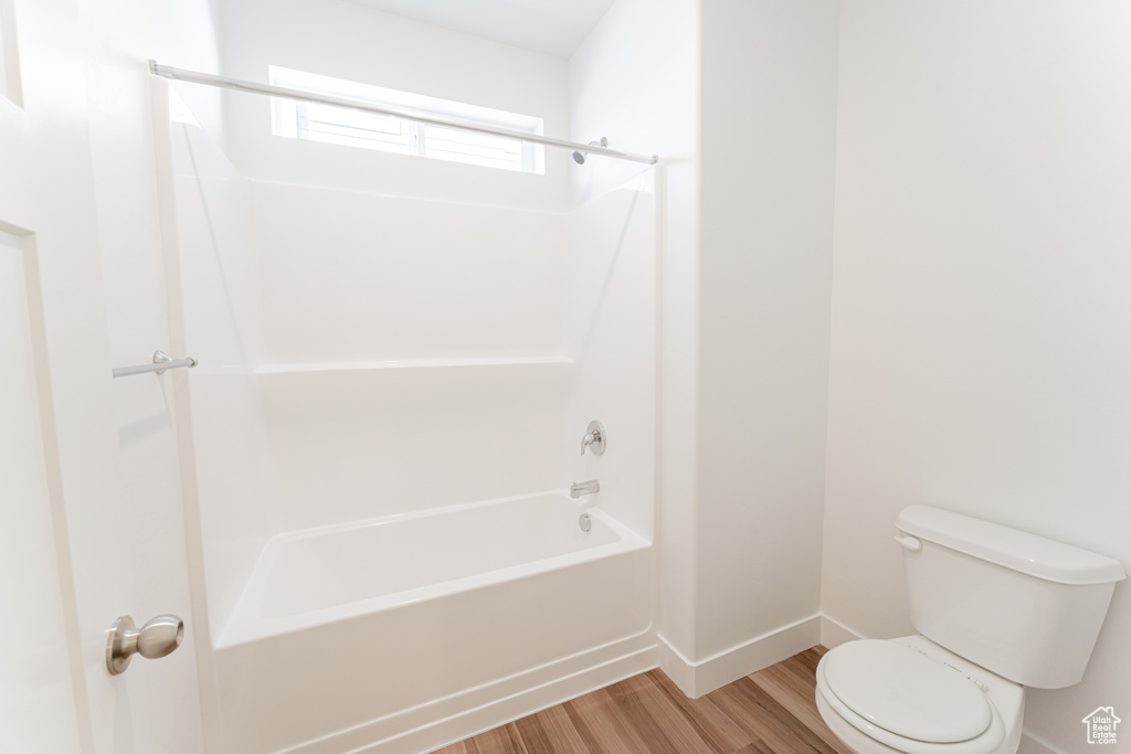 Bathroom with hardwood / wood-style flooring, toilet, and tub / shower combination