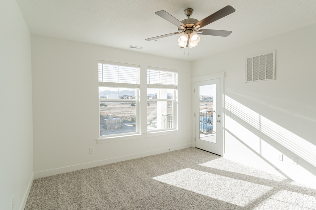 Carpeted empty room featuring a wealth of natural light and ceiling fan