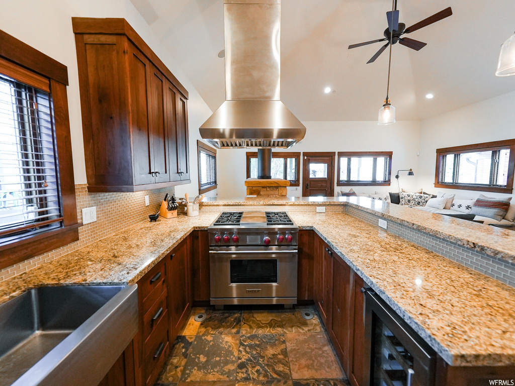 Kitchen featuring wine cooler, ceiling fan, backsplash, designer stove, and island range hood