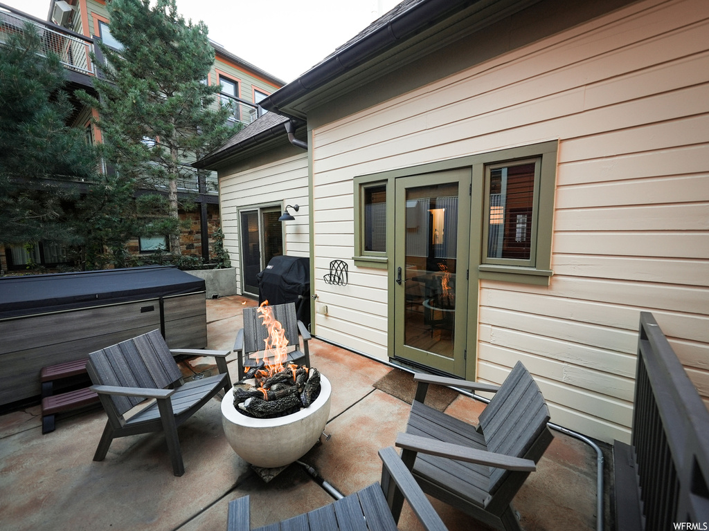 Deck with a grill, a hot tub, an outdoor fire pit, and a patio