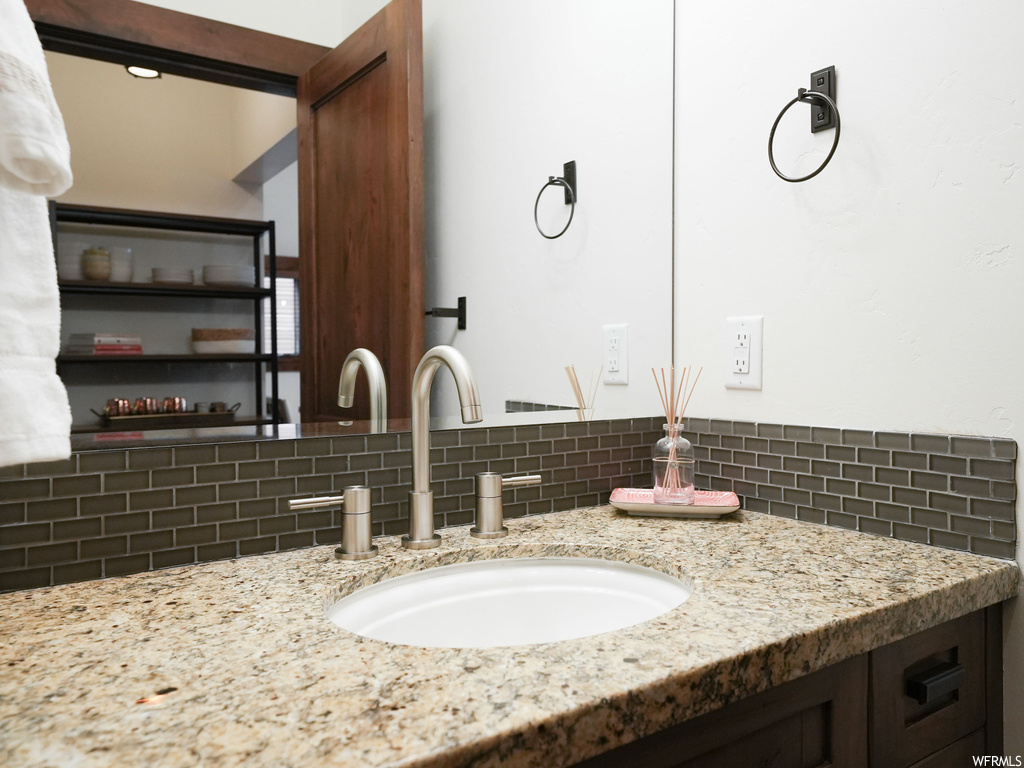 Bathroom featuring vanity with extensive cabinet space and tasteful backsplash