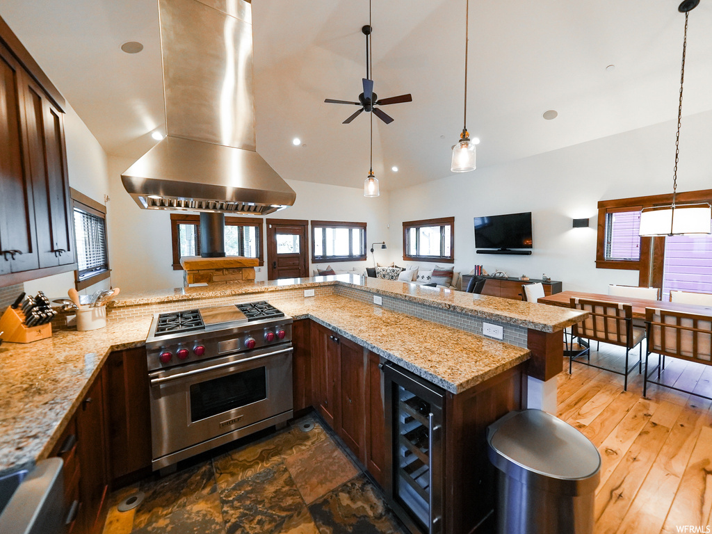 Kitchen featuring beverage cooler, premium stove, island range hood, dark brown cabinets, and ceiling fan