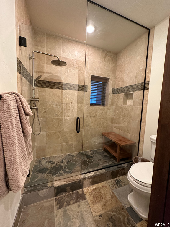 Bathroom featuring tile floors, an enclosed shower, toilet, and tile walls