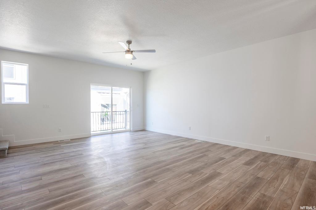 Unfurnished room with light hardwood / wood-style floors, ceiling fan, a textured ceiling, and a healthy amount of sunlight