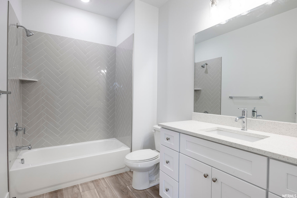 Full bathroom with oversized vanity, hardwood / wood-style flooring, toilet, and tiled shower / bath