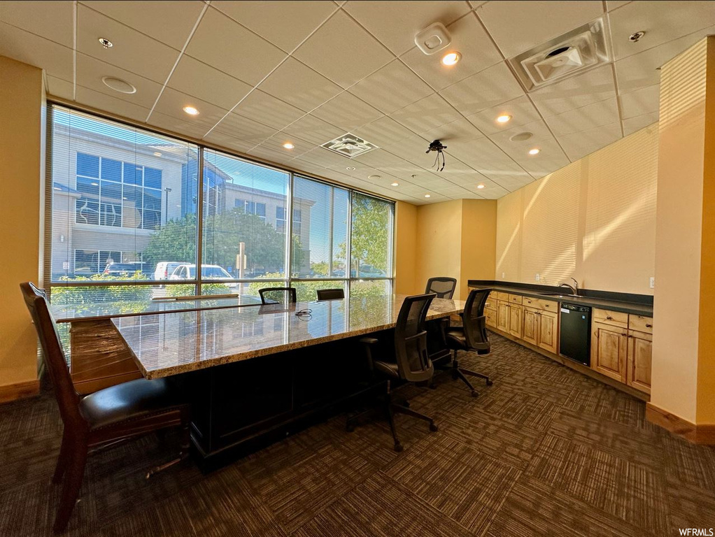 Carpeted office with a drop ceiling and expansive windows