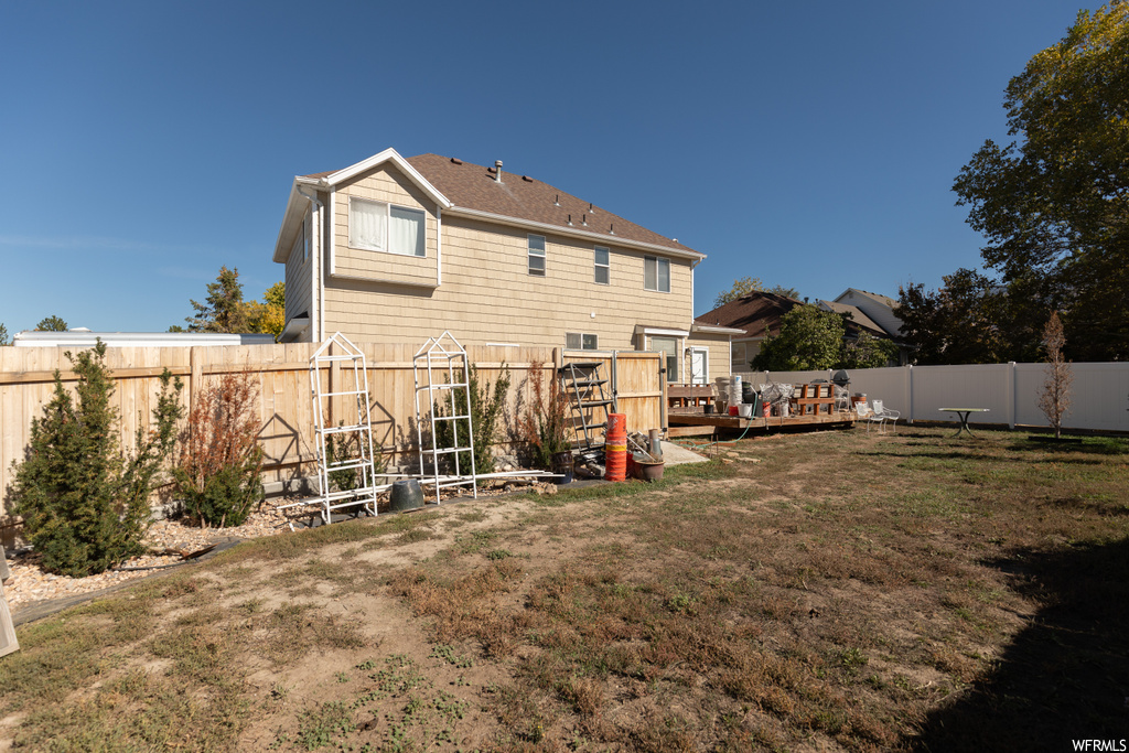 Back of property featuring a yard and a wooden deck