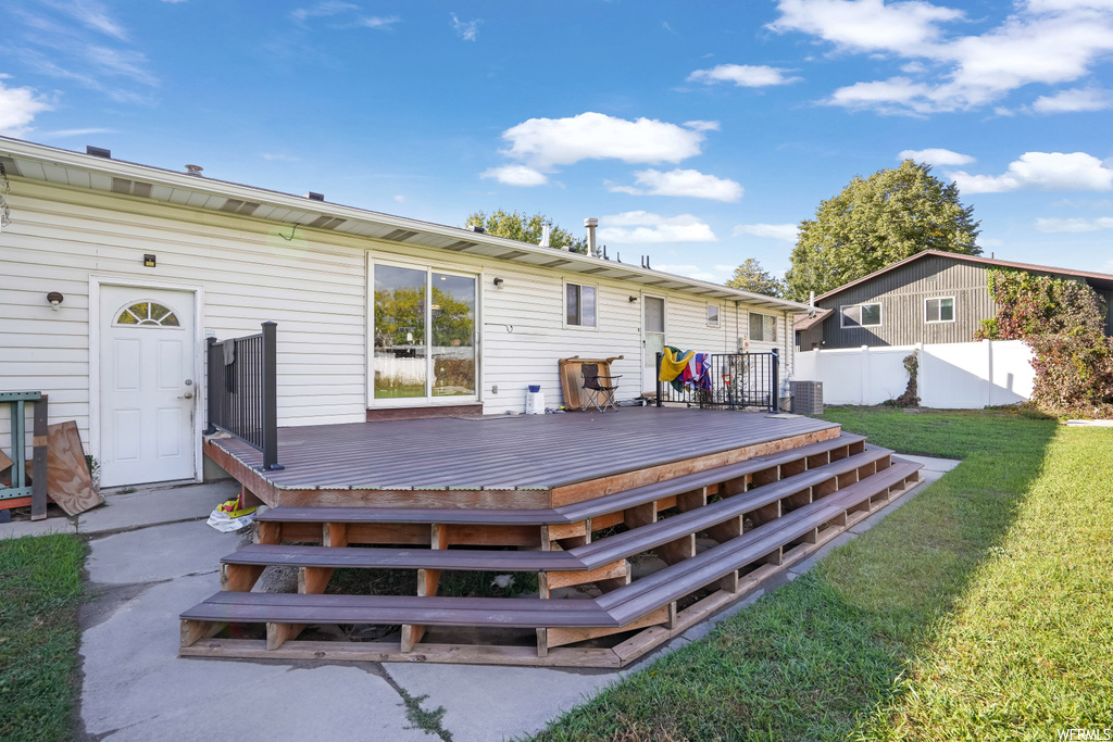 Back of property featuring a lawn and a wooden deck