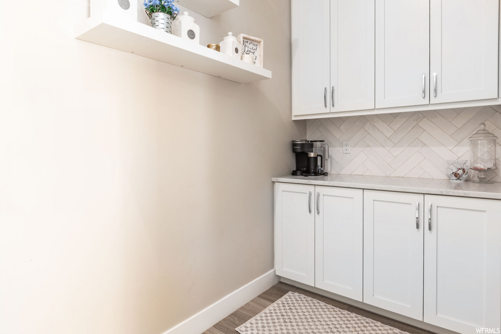 Kitchen featuring light hardwood / wood-style floors, backsplash, and white cabinets