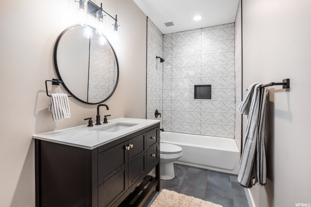 Full bathroom with vanity, tile floors, toilet, and tiled shower / bath