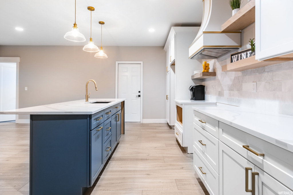 Kitchen featuring sink, tasteful backsplash, light hardwood / wood-style flooring, and white cabinets
