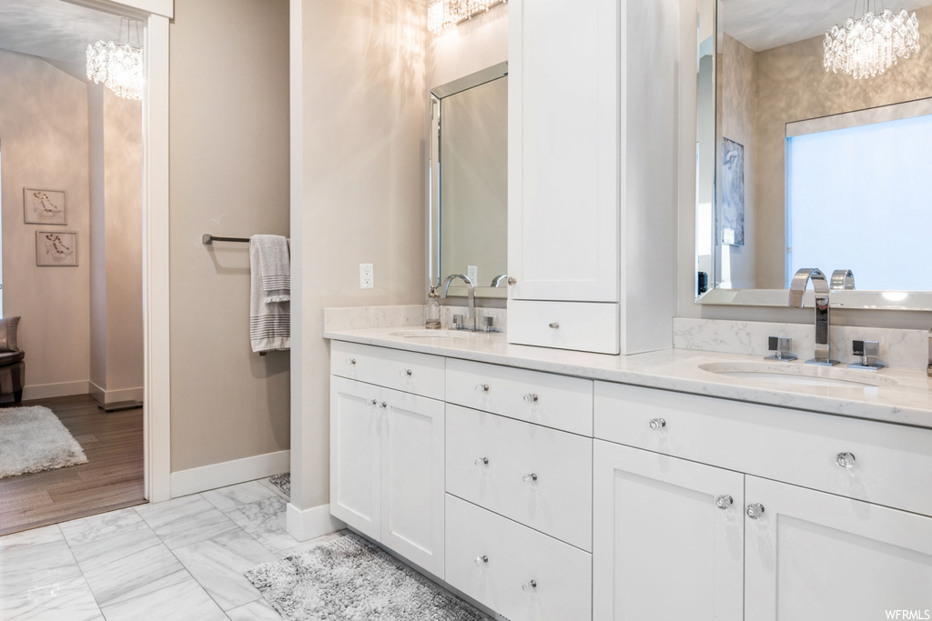 Bathroom with tile flooring, large vanity, a notable chandelier, and dual sinks