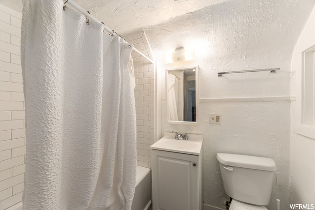 Full bathroom featuring a textured ceiling, shower / tub combo, vanity, and toilet