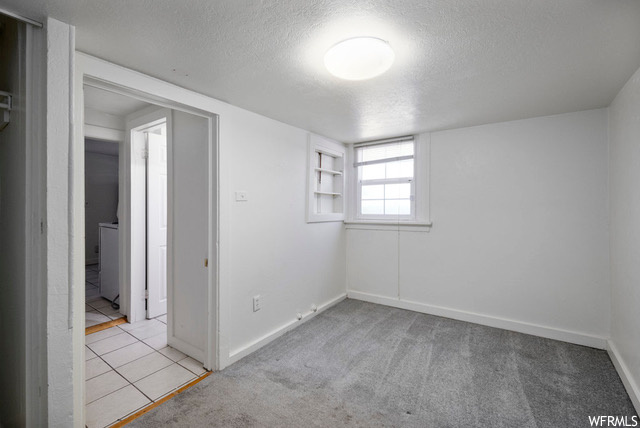 Spare room featuring washer / clothes dryer, light tile floors, and a textured ceiling