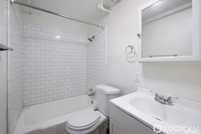 Full bathroom with toilet, oversized vanity, and tiled shower / bath combo