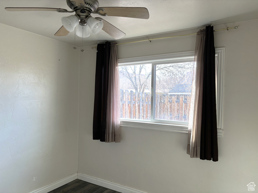 Unfurnished room with a healthy amount of sunlight, dark hardwood / wood-style floors, and ceiling fan