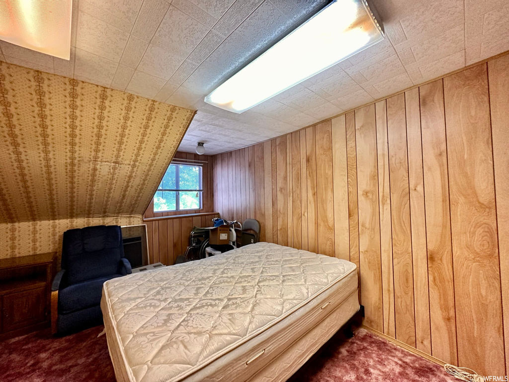 Carpeted bedroom with lofted ceiling and wooden walls