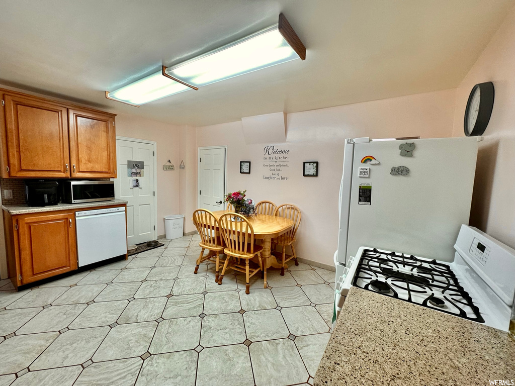 Kitchen featuring white appliances, backsplash, and light tile floors