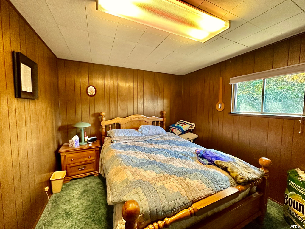 Bedroom featuring wooden walls and dark carpet