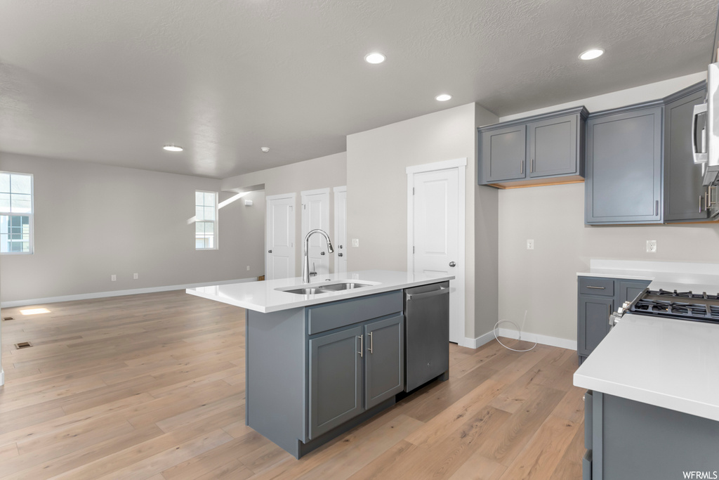 Kitchen with sink, gray cabinetry, a kitchen island with sink, light wood-type flooring, and dishwasher