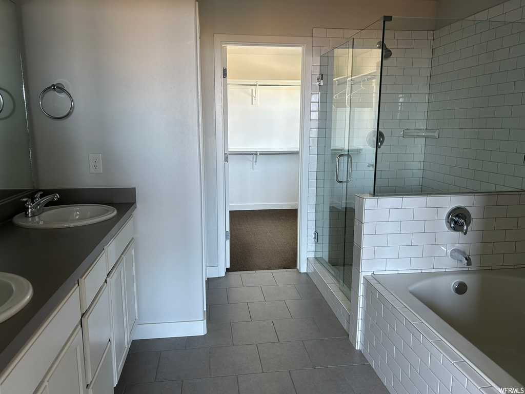 Bathroom featuring tile floors, separate shower and tub, vanity with extensive cabinet space, and dual sinks
