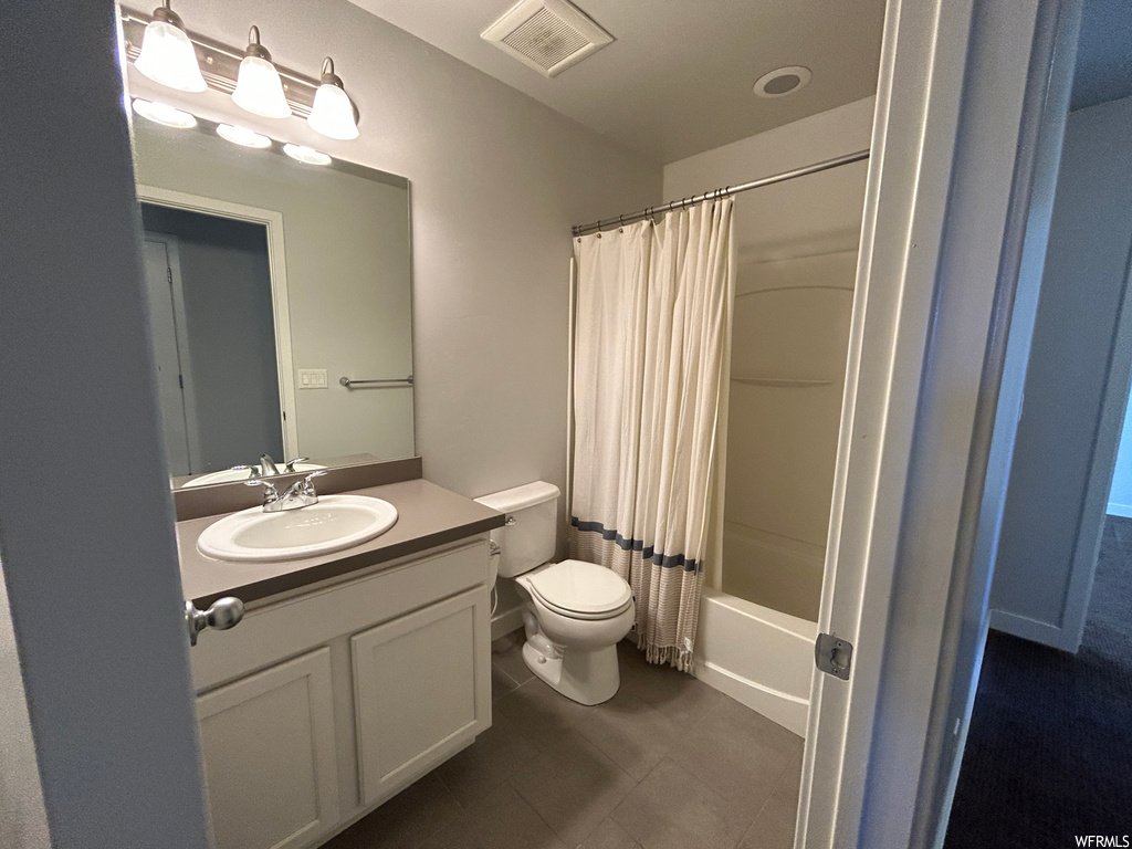 Full bathroom featuring toilet, shower / bath combination with curtain, oversized vanity, and tile flooring
