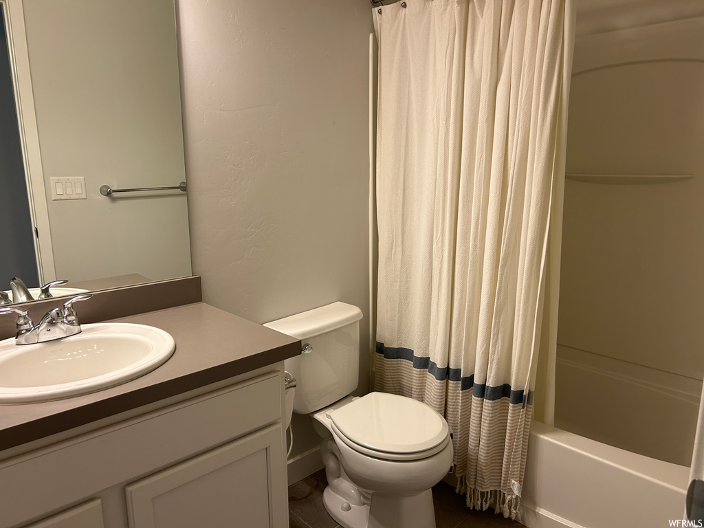 Full bathroom featuring large vanity, shower / tub combo, tile floors, and toilet