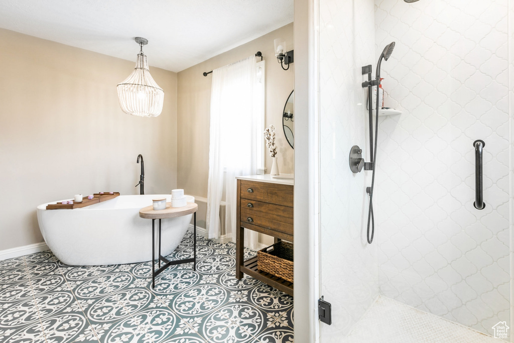 Bathroom featuring tiled shower, vanity, and tile flooring