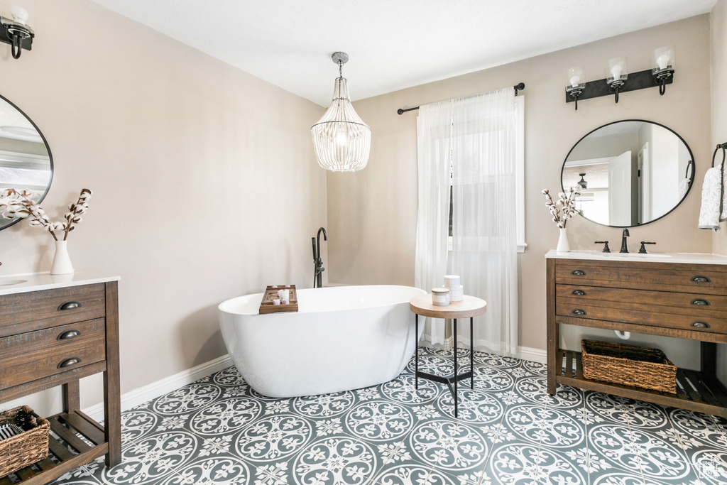 Bathroom with vanity, a bathtub, a notable chandelier, and tile floors