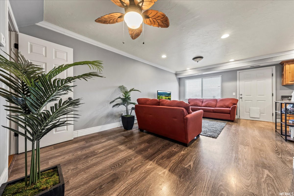 Living room featuring dark hardwood / wood-style flooring, ceiling fan, and ornamental molding
