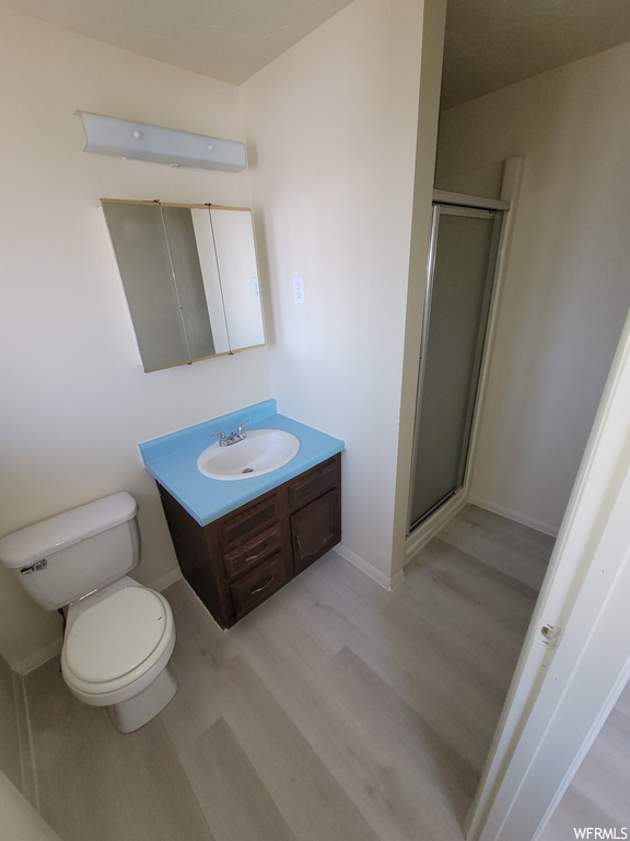 Bathroom with large vanity, wood-type flooring, toilet, and walk in shower