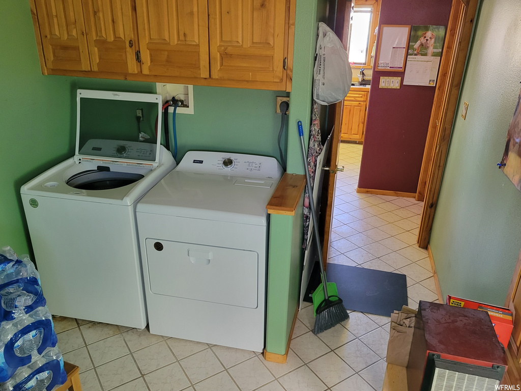 Laundry area featuring light tile flooring, cabinets, washer and clothes dryer, and hookup for a washing machine