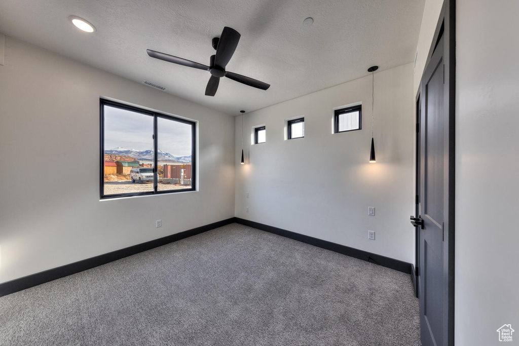 Spare room with ceiling fan, dark carpet, and a textured ceiling