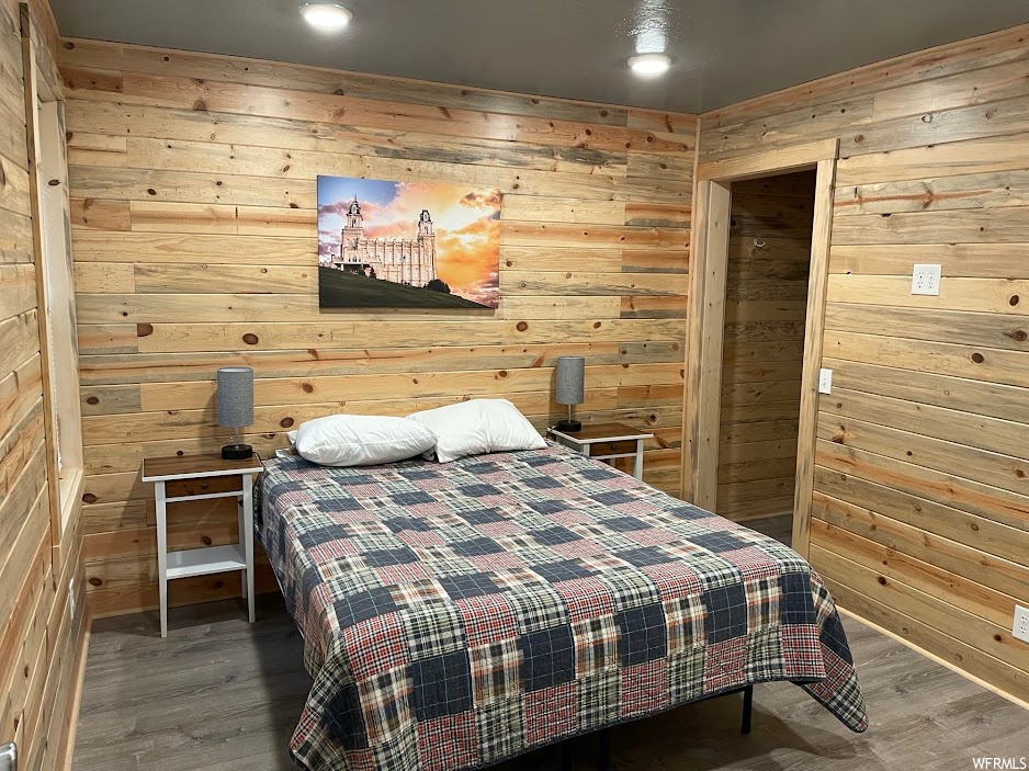 Bedroom with dark hardwood / wood-style flooring and wooden walls