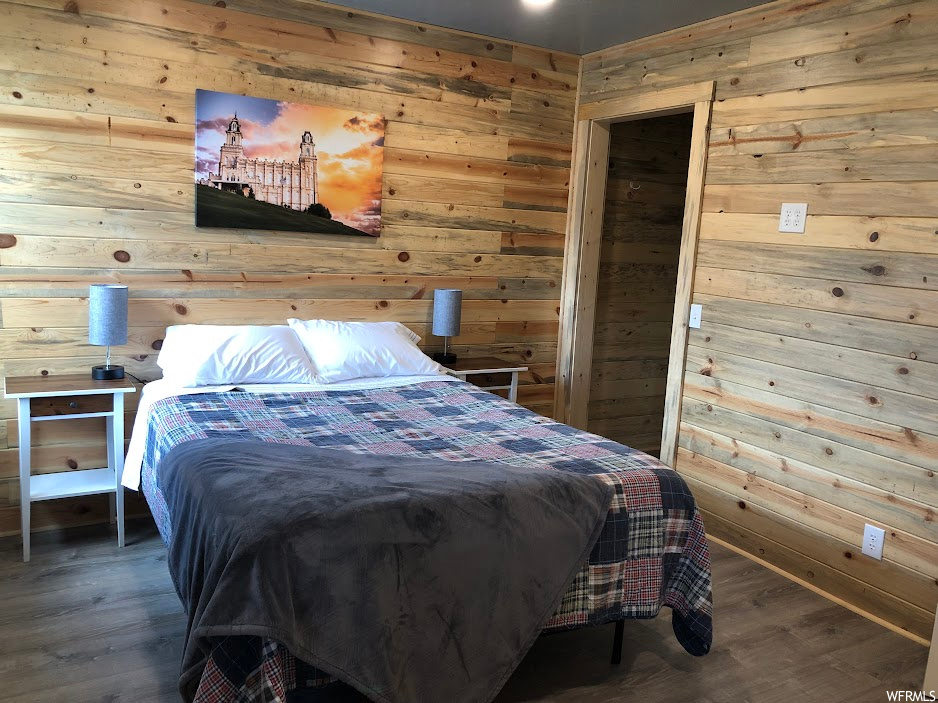 Bedroom featuring dark hardwood / wood-style floors and wood walls
