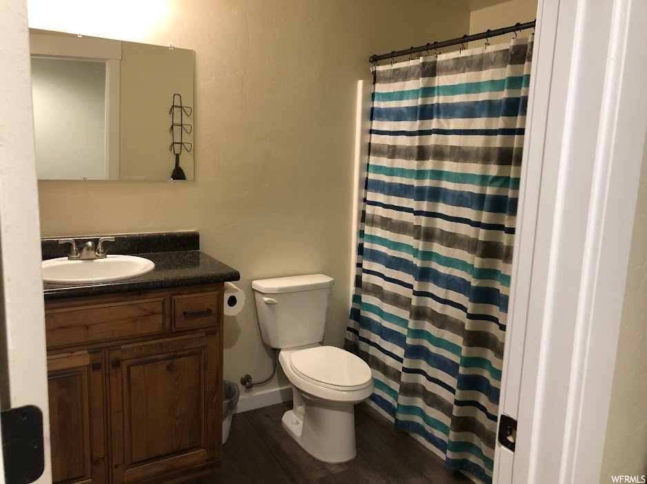 Bathroom with hardwood / wood-style floors, vanity with extensive cabinet space, and toilet