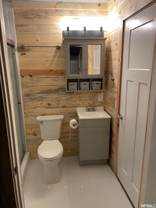 Bathroom with an enclosed shower, toilet, wood walls, tile floors, and vanity with extensive cabinet space