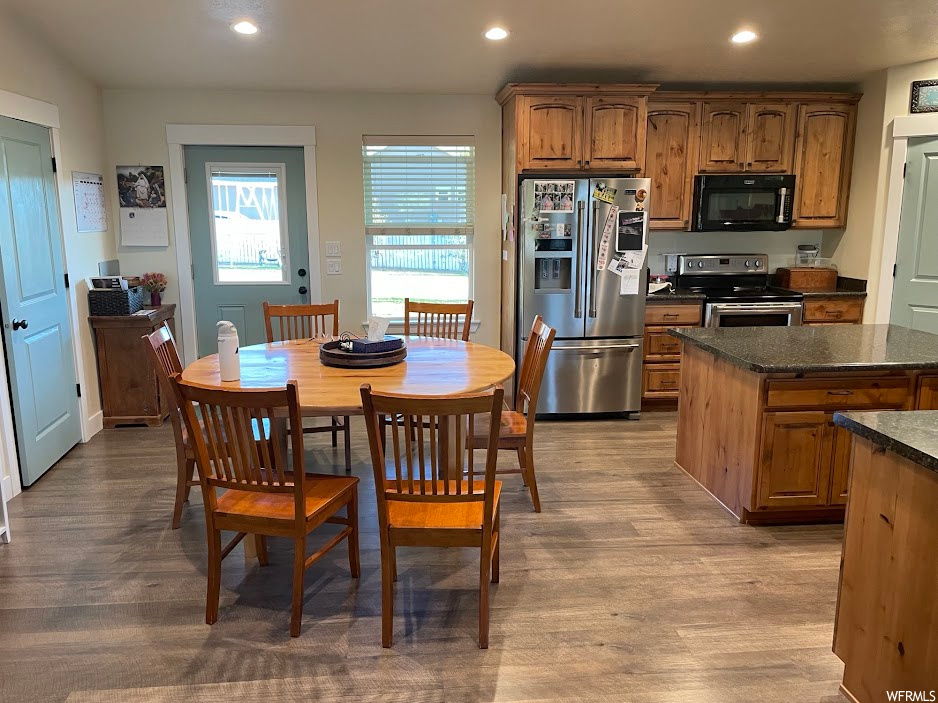 Kitchen featuring stainless steel appliances, a kitchen island, dark stone countertops, and light hardwood / wood-style flooring