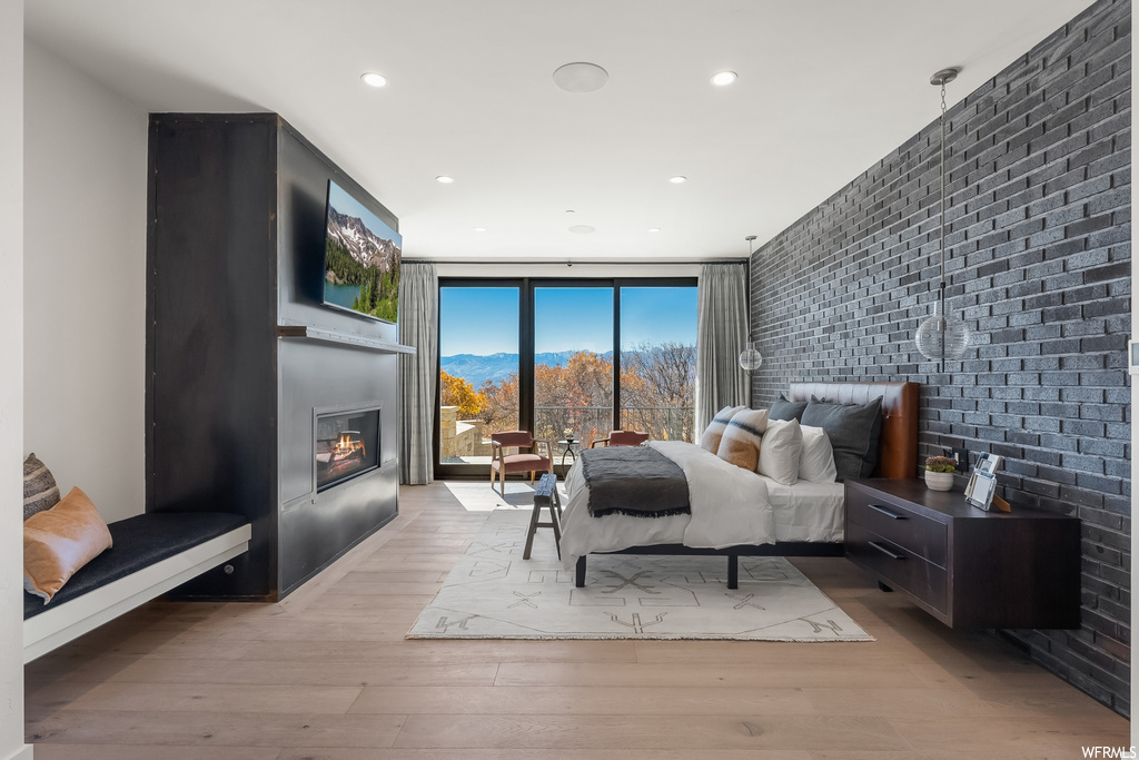 Bedroom with light hardwood / wood-style floors, a fireplace, and brick wall