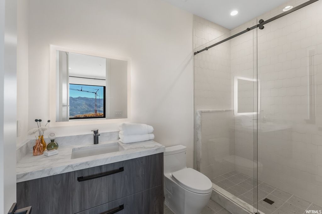 Bathroom with an enclosed shower, vanity with extensive cabinet space, and toilet