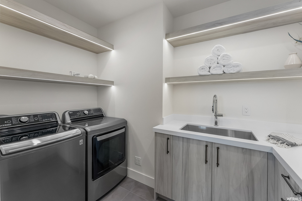 Laundry room featuring washer and dryer, sink, cabinets, and light tile floors