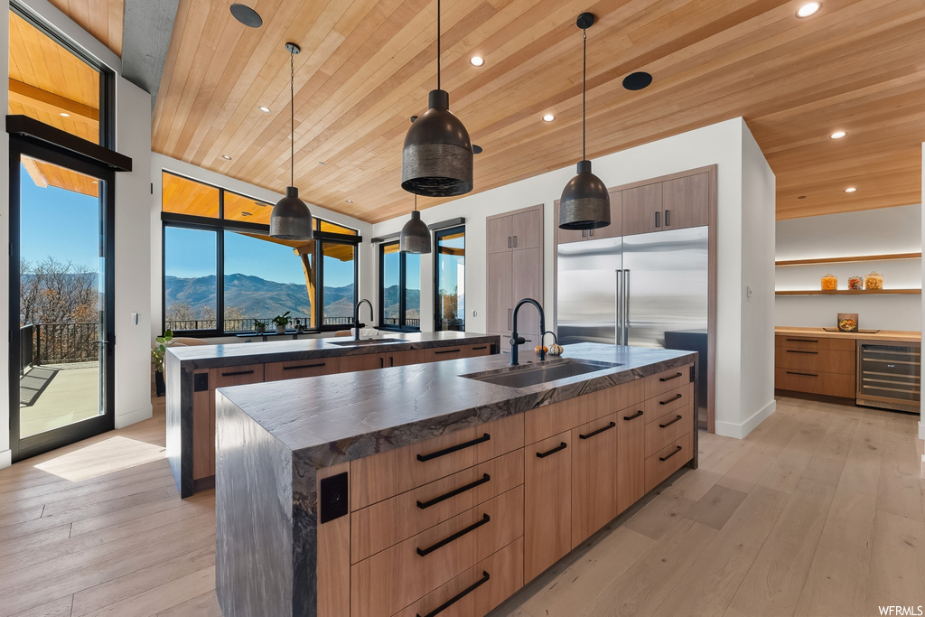 Kitchen with decorative light fixtures, an island with sink, light wood-type flooring, and a mountain view