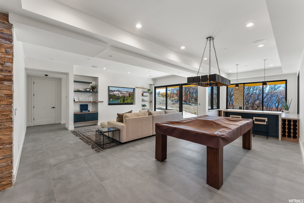 Rec room featuring built in shelves, billiards, a tray ceiling, and light tile floors