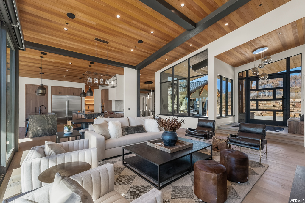 Living room featuring sink, light hardwood / wood-style flooring, wood ceiling, a towering ceiling, and beamed ceiling