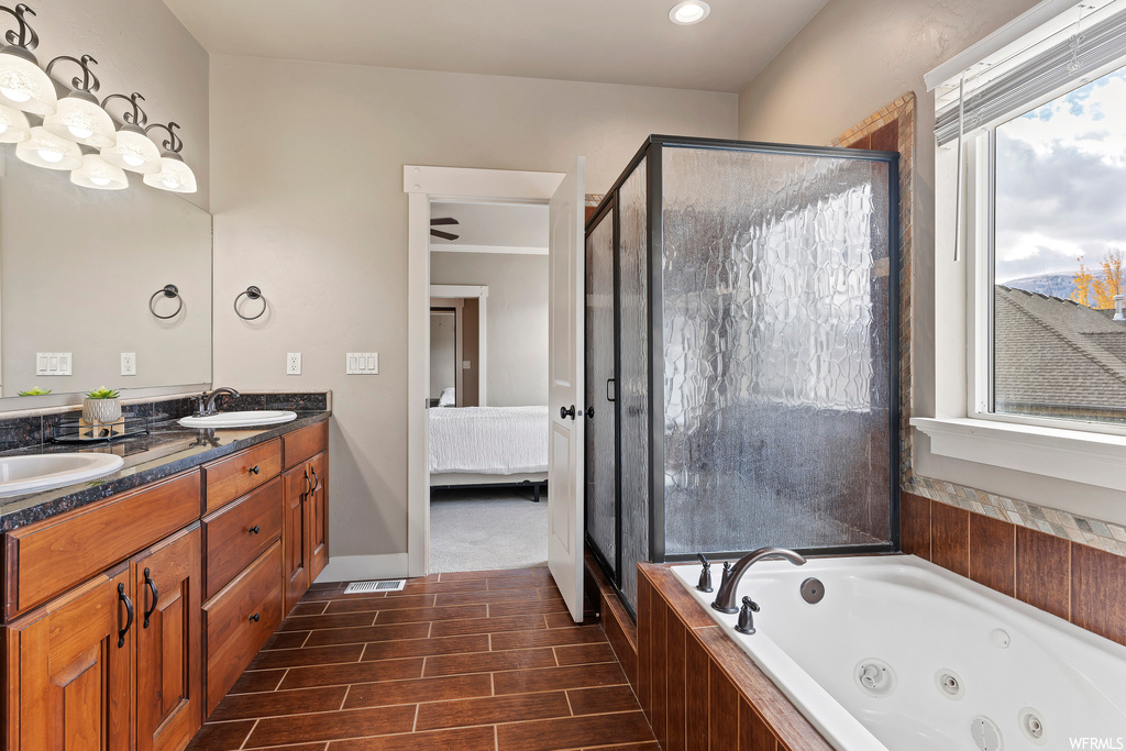 Bathroom featuring separate shower and tub, dual bowl vanity, and tile floors