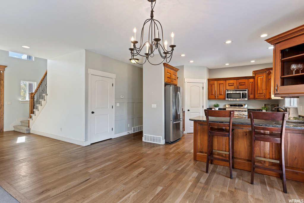 Kitchen with light wood-type flooring, a notable chandelier, and appliances with stainless steel finishes