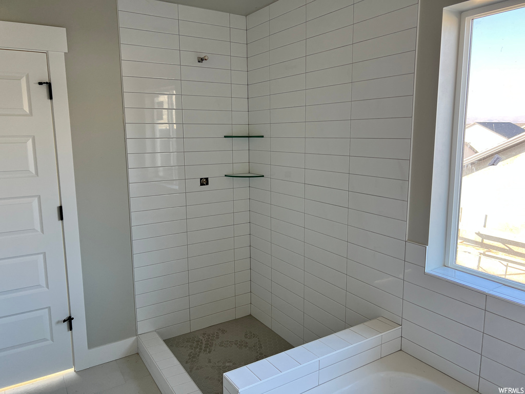 Bathroom featuring a wealth of natural light, tile floors, and a tile shower