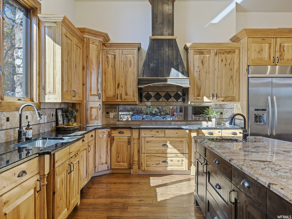 Kitchen featuring backsplash, dark stone countertops, dark hardwood / wood-style floors, and stainless steel built in refrigerator