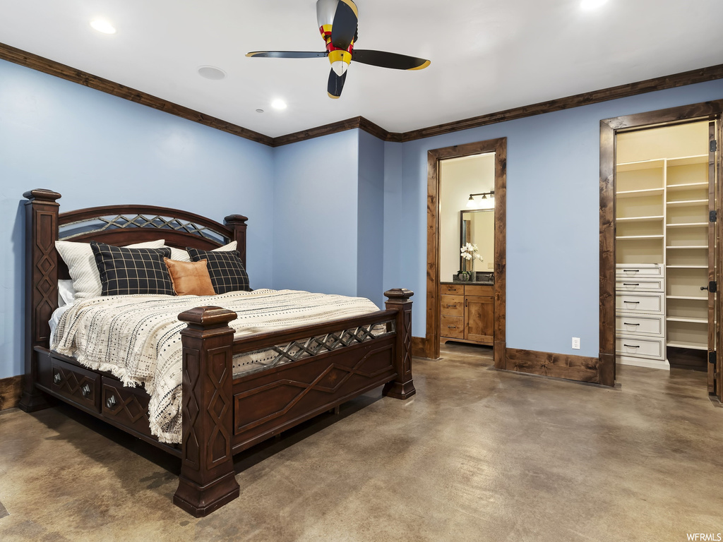 Bedroom with connected bathroom, a walk in closet, ornamental molding, a closet, and ceiling fan