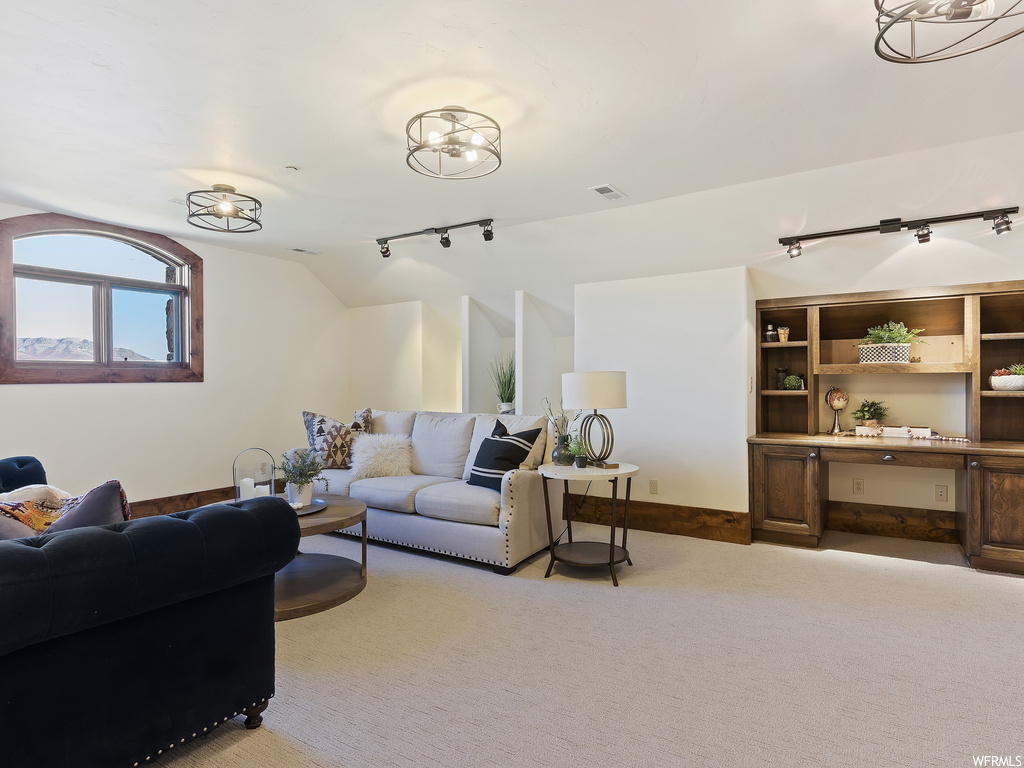 Living room featuring rail lighting, a notable chandelier, and light colored carpet